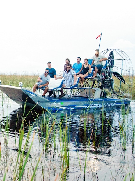 Airboat with tourists exploring Everglades wetlands during a night tour.