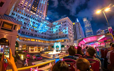 Open-top bus tour passing The Peninsula Hotel in Hong Kong at night.