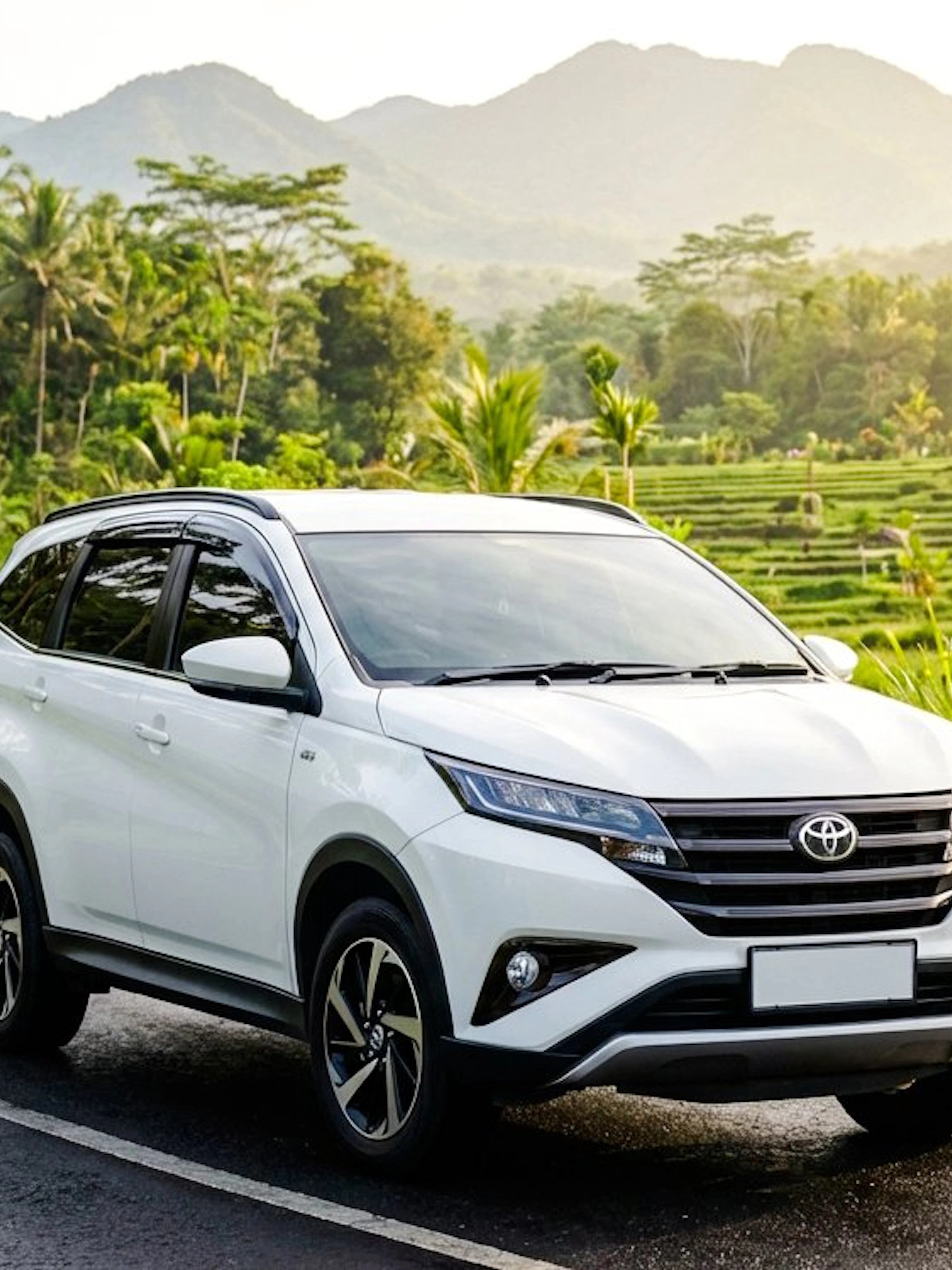 Toyota Rush on a scenic winding road with lush greenery and mountains in the background.