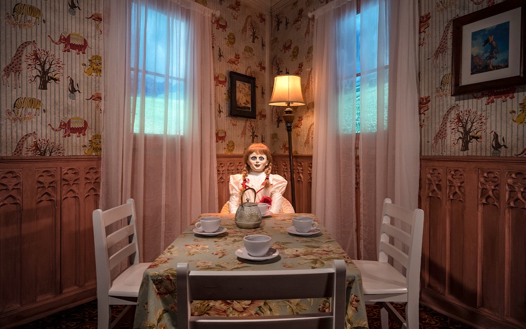 Wax figure of Annabelle from The Conjuring at a tea table in Madame Tussauds, New York horror zone.