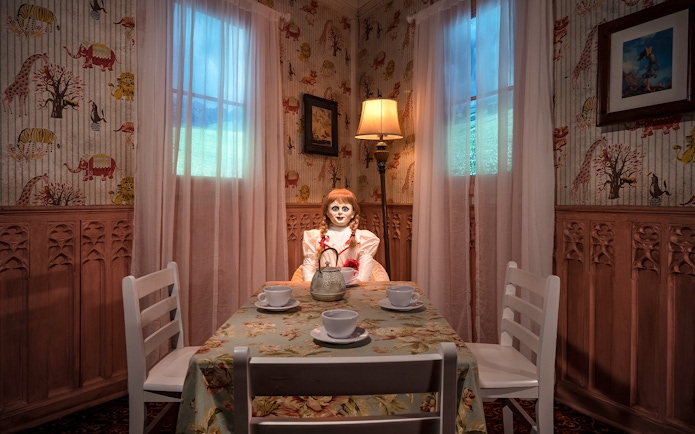 Wax figure of Annabelle from The Conjuring at a tea table in Madame Tussauds, New York horror zone.
