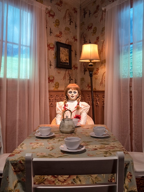 Wax figure of Annabelle from The Conjuring at a tea table in Madame Tussauds, New York horror zone.