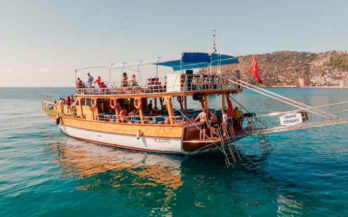 Boat with tourists on Alanya Boat Day Tour, sailing near the coast of Alanya, Turkey.