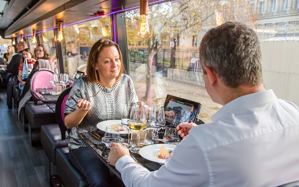 Couple dining inside Bus Toqué Paris with scenic city view.