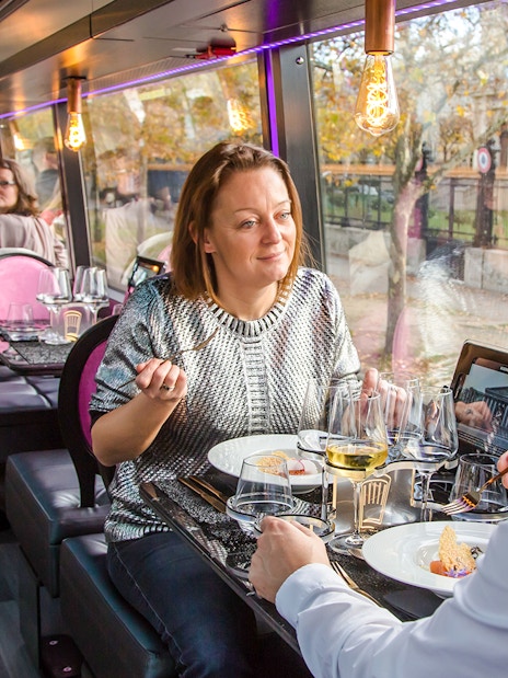 Couple dining inside Bus Toqué Paris with scenic city view.