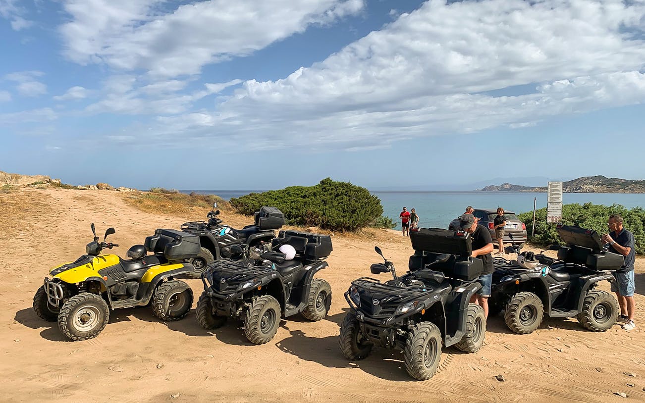 Quad bikes parked on a sandy trail with a view of the sea in Santa Teresa di Gallura.