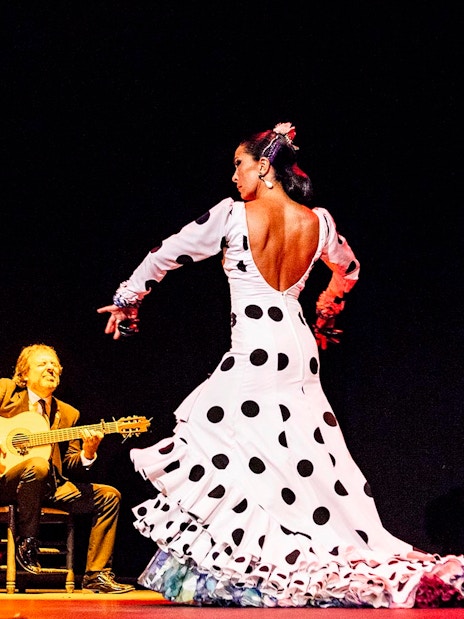 Flamenco dancer performing on stage with musicians during Pasión espectáculo flamenco.