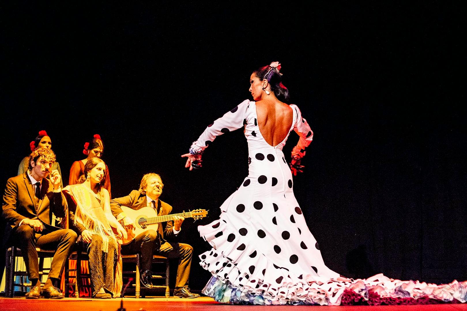 Flamenco dancer performing on stage with musicians during Pasión espectáculo flamenco.