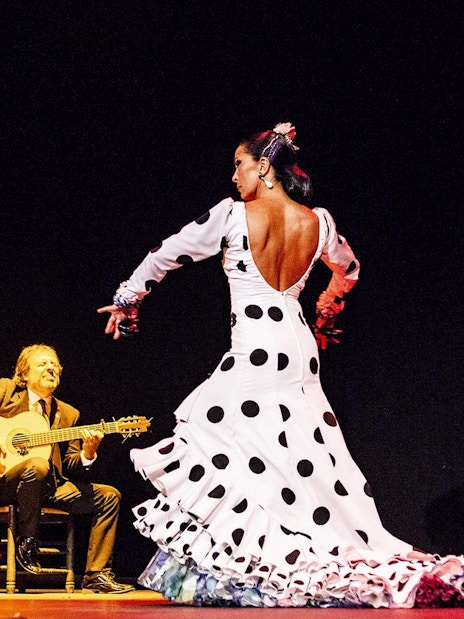 Flamenco dancer performing on stage with musicians during Pasión espectáculo flamenco.