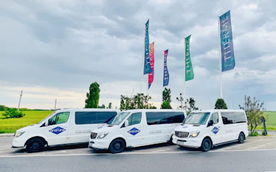 Shuttle vans parked at Therme Bucuresti with colorful flags in the background.