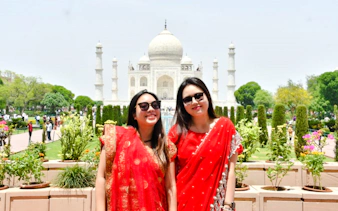 Visitors in red attire at the Taj Mahal, Agra, during a guided day tour.