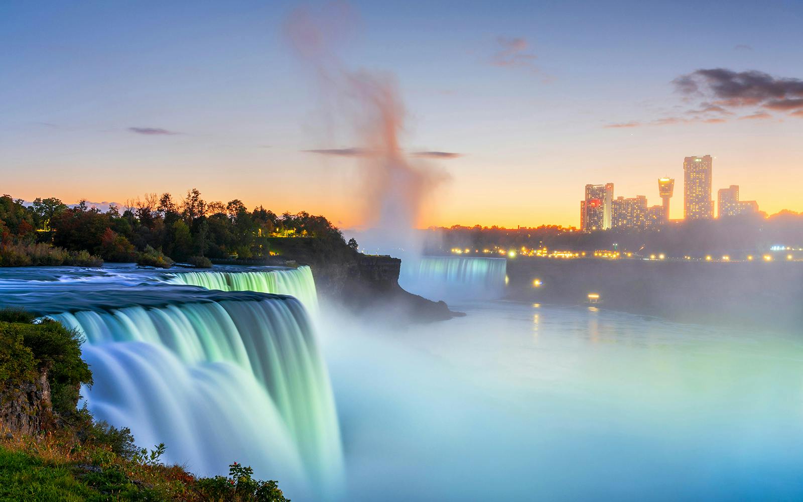 Niagara Falls at sunset with city skyline in the background, USA evening tour.