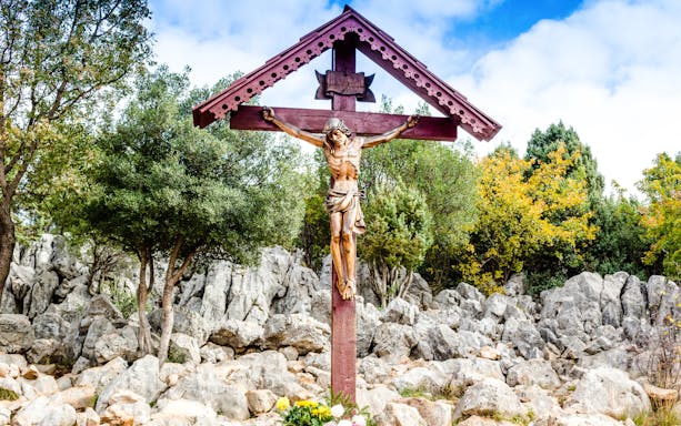 Cross on Apparition Hill surrounded by rocks and trees, Bosnia and Herzegovina.