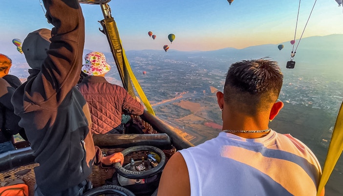 Hot air balloon passengers floating above Teotihuacan pyramids, Mexico.