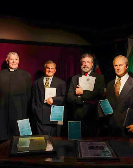 Wax figures of historical figures holding documents at Wax Museum Dublin.