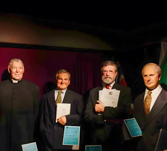 Wax figures of historical figures holding documents at Wax Museum Dublin.