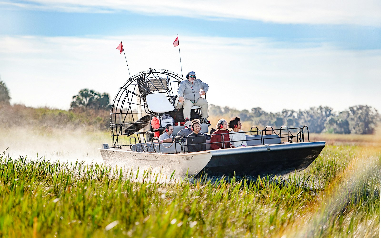 Airboat with tourists gliding through marshes on Boggy Creek Airboat Tour, Orlando.