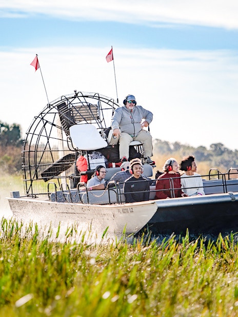 Airboat with tourists gliding through marshes on Boggy Creek Airboat Tour, Orlando.