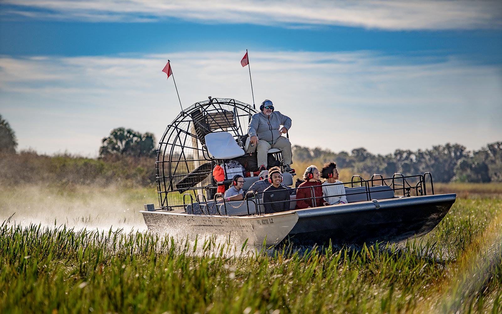 Guests on an airboat tour at Boggy Creek, Florida, gliding through marshlands.