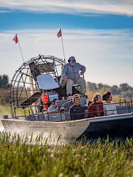 Guests on an airboat tour at Boggy Creek, Florida, gliding through marshlands.