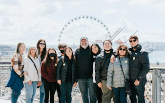 Group of people on a Chef Guided Food Tour at Pike Place Market with Seattle Great Wheel in background.