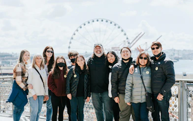 Group of people on a Chef Guided Food Tour at Pike Place Market with Seattle Great Wheel in background.