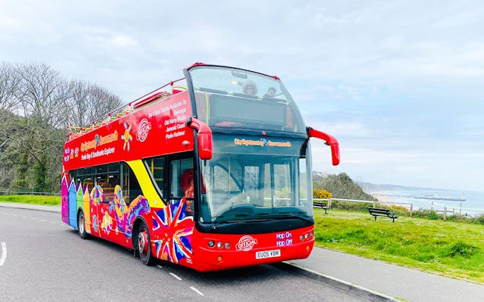 Bournemouth hop-on hop-off bus near Poole Harbour with coastal view.