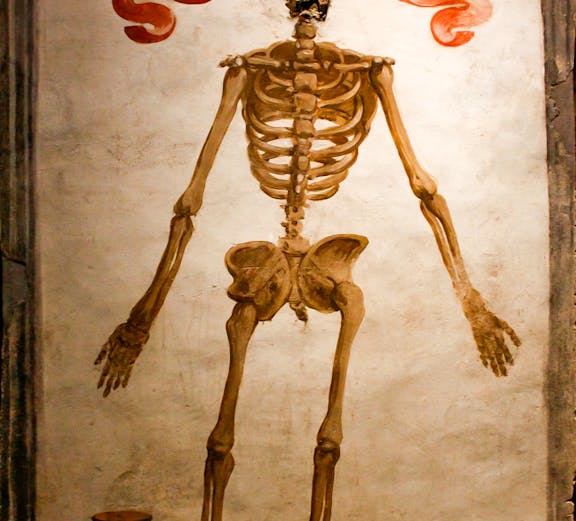 Skeleton mural with hourglass and crown in Catacombs of San Gaudioso, Naples.