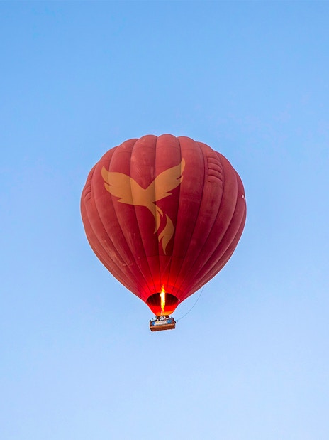 Hot air balloon in flight over Ras Al Khaimah against clear blue sky.
