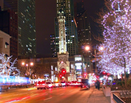 Chicago Water Tower at night with festive Christmas lights and bustling street traffic.