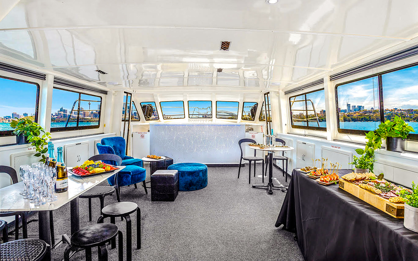 Interior of a boat set for a Golden Glow sunset harbour cruise in Sydney, featuring tables with food and drinks.