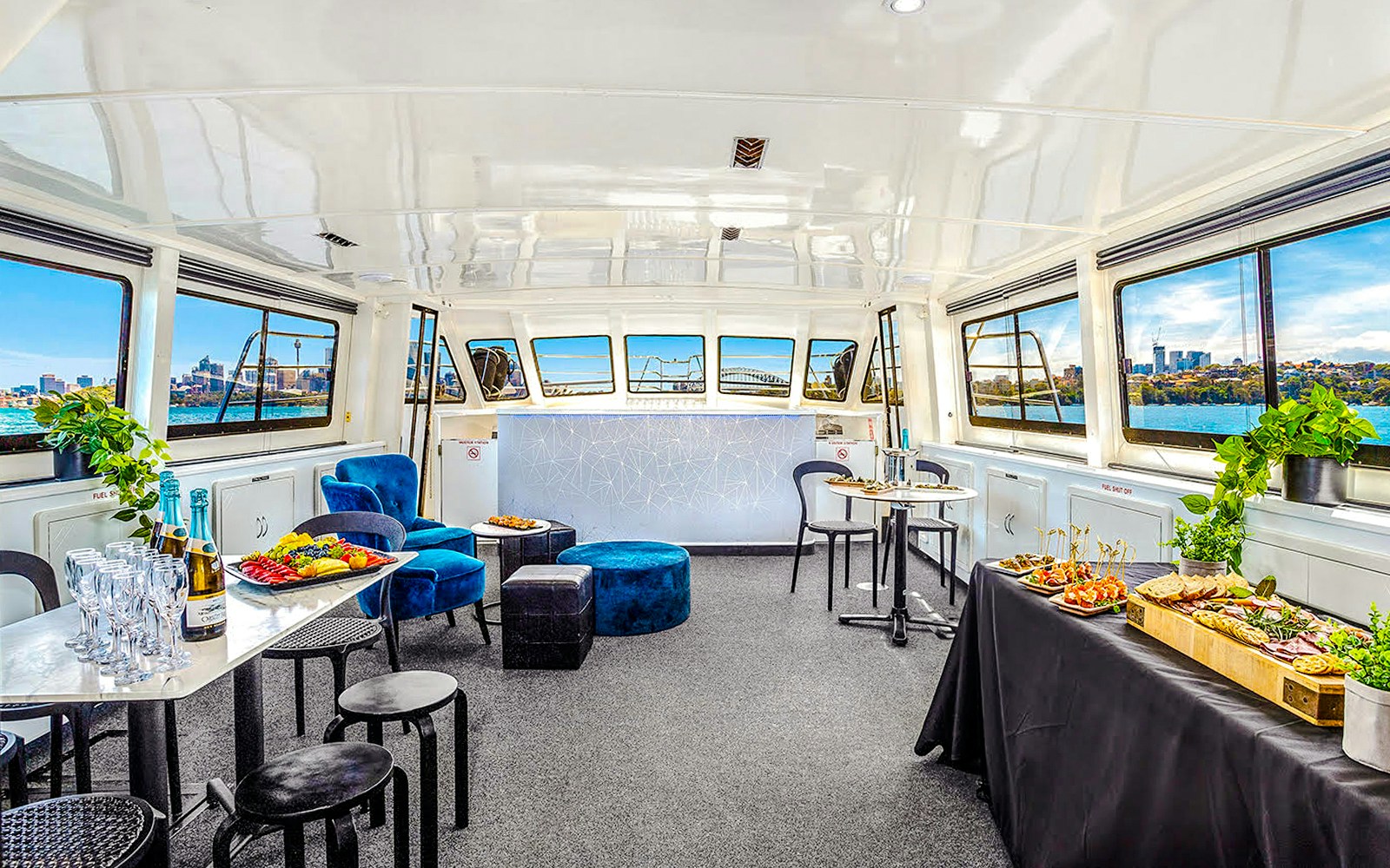 Interior of a boat set for a Golden Glow sunset harbour cruise in Sydney, featuring tables with food and drinks.