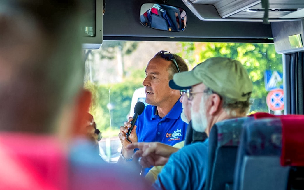 Tour guide speaking to passengers on a bus during Pompeii and Positano day trip from Naples.