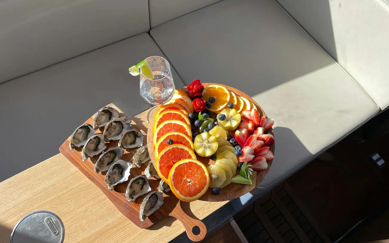 Oysters and sliced fruits on a wooden platter during Hobart Half-Day Fishing, Diving & Gourmet Cruise.