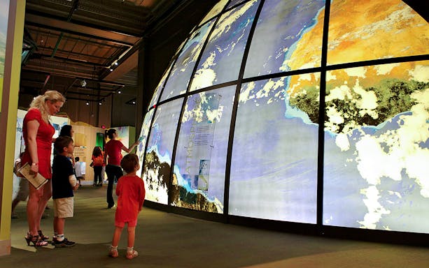 Visitors exploring large illuminated globe at Franklin Institute.