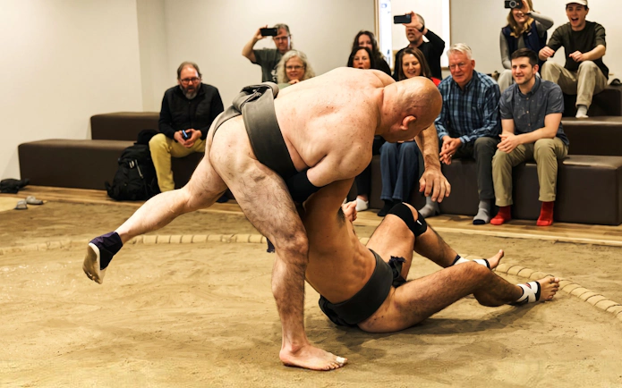 Sumo wrestlers in action during a live show in Osaka with an audience watching.