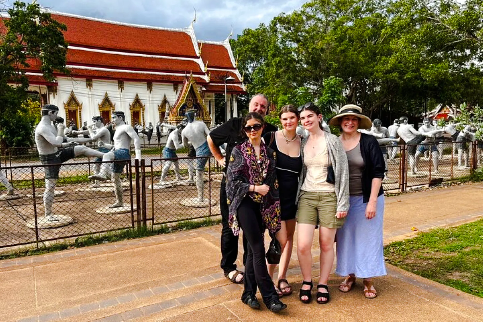 Group visiting Muay Thai statues at a temple near Amphawa Floating Market, Thailand.