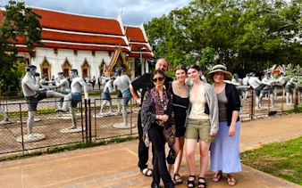 Group visiting Muay Thai statues at a temple near Amphawa Floating Market, Thailand.