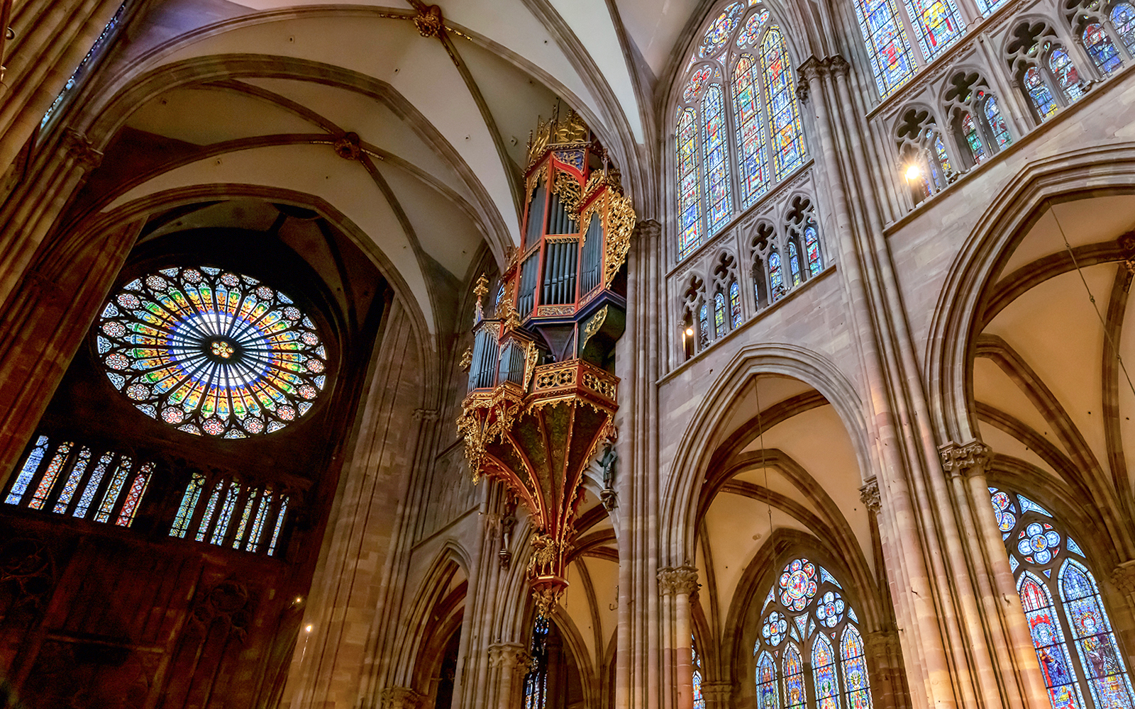 Notre Dame Paris transept interior with stained glass windows and vaulted ceilings.