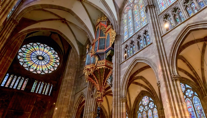 Notre Dame Paris transept interior with stained glass windows and vaulted ceilings.