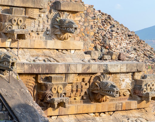 Temple of Quetzalcoatl with intricate carved stone serpent heads in Teotihuacan, Mexico.