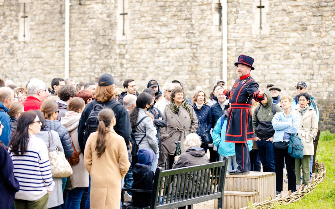 Guide in traditional attire leading a group tour at the Tower of London.