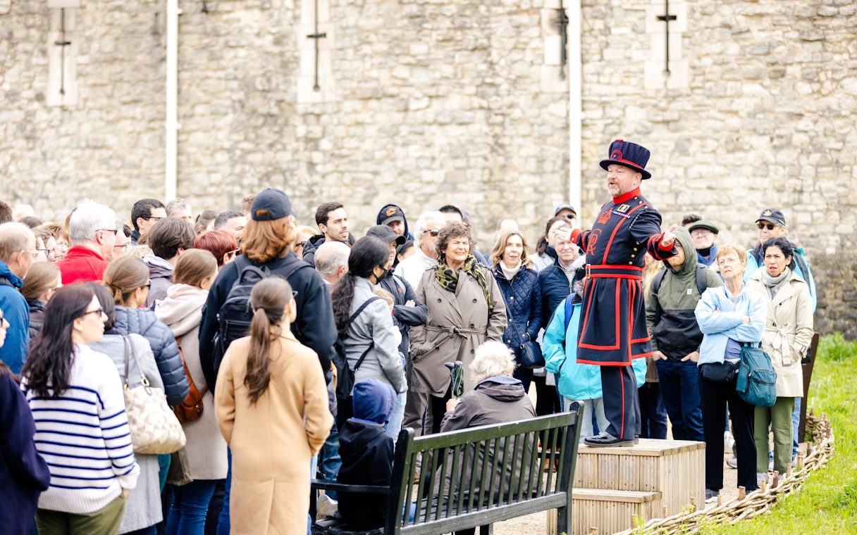 Guide in traditional attire leading a group tour at the Tower of London.