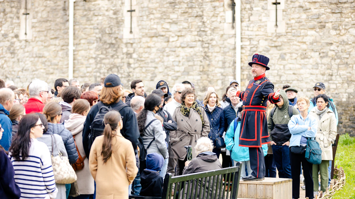Guide in traditional attire leading a group tour at the Tower of London.