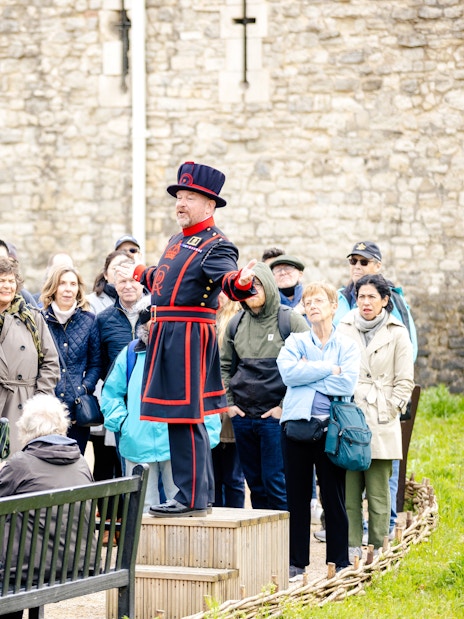 Guide in traditional attire leading a group tour at the Tower of London.