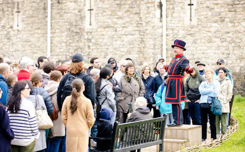 Guide in traditional attire leading a group tour at the Tower of London.