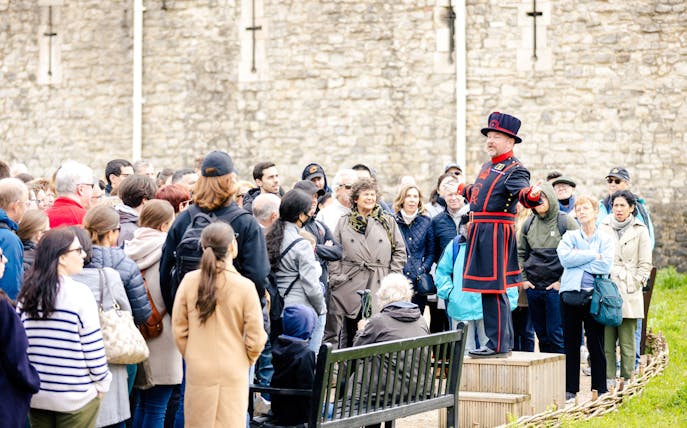 Guide in traditional attire leading a group tour at the Tower of London.