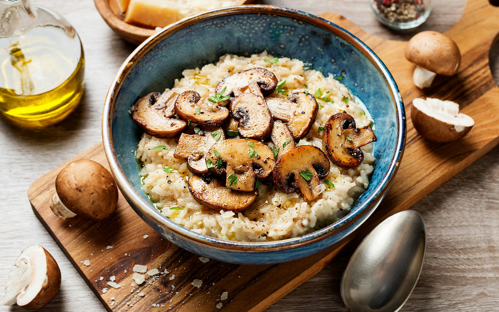 Mushroom risotto in a blue bowl with fresh herbs and sliced mushrooms.