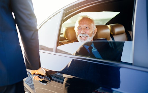Senior man in suit sitting in airport transfer car.