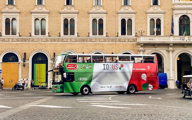 Rome hop-on hop-off bus in front of historic building.